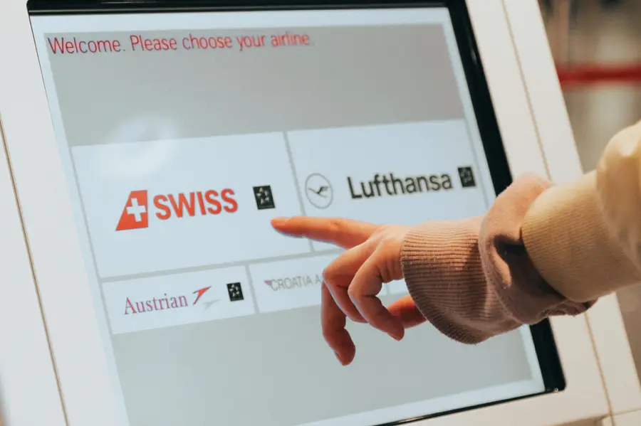 Close-up of a hand using a touchscreen for airline check-in, highlighting the mistake of pet owners forgetting to reserve an in-cabin spot for their pets during international pet relocation.