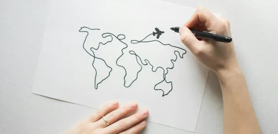 Pair of hands drawing a world map and airplane, signifying the planning of international pet travel and transatlantic pet relocation.